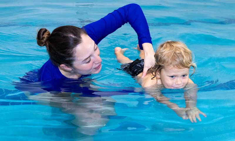 Njswim teacher teaching a young child how to swim