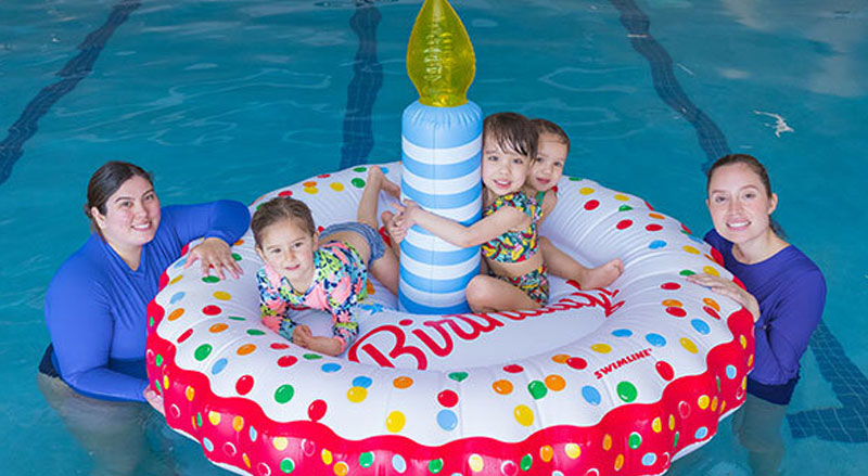 Three kids celebrating on a birthday party float in the Njswim pool with two swim teachers attending