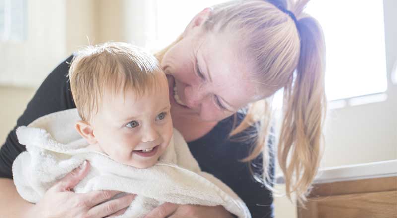 A woman holds a baby boy who is wrapped in a towel