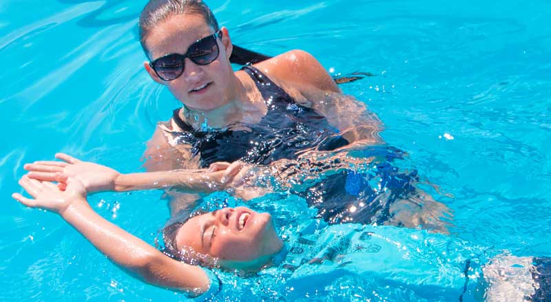 A Njswim teacher assisting a boy in a pool during a swimming lesson