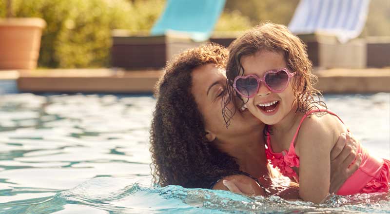 A woman and young daughter having fun together in pool