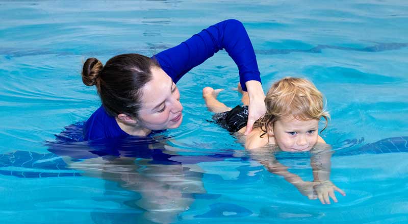 A young boy learns essential water safety skills with his NJSwim instructor in our warm, welcoming pool environment