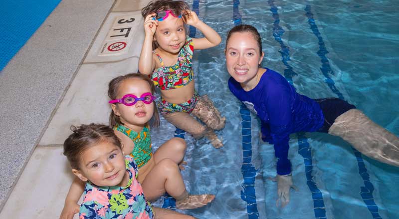 A Njswim teacher in the pool with three young students