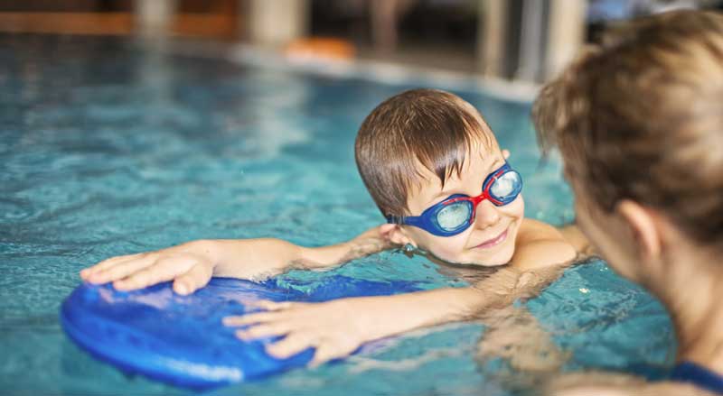 A little boy and his swim teacher in the pool during a swim class