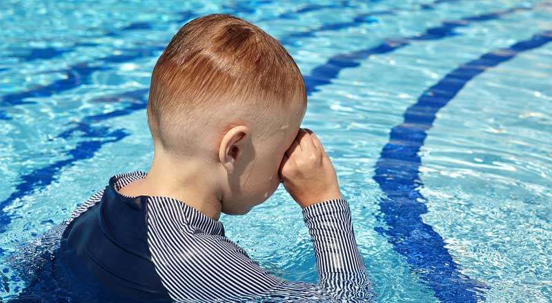 A young boy crying in a swimming pool