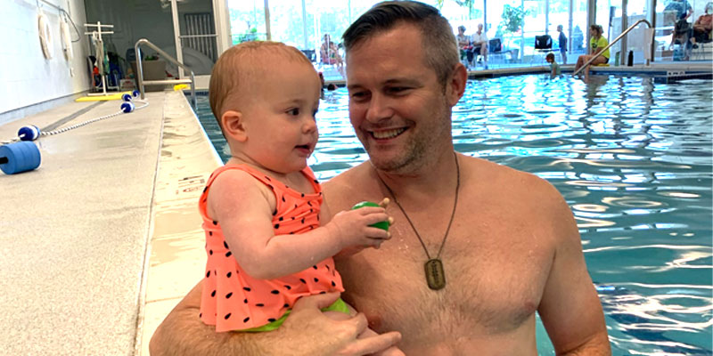 Father holding his baby at the edge of a swimming pool