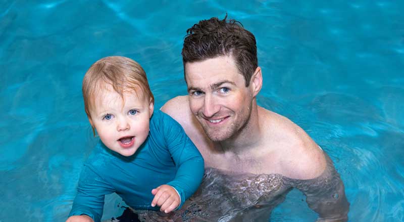 A father and baby enjoying time in the pool during a Water Babies class