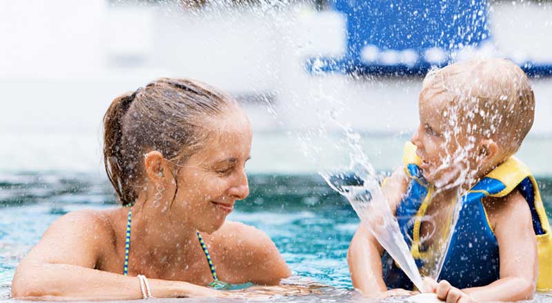 Woman and child enjoying time in a pool, splashing and playing