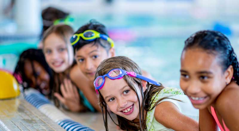 Group of young kids in a pool during a water safety class