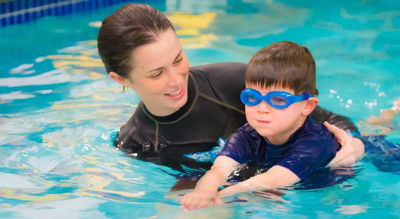 An Njswim teacher giving a swim lesson to a young boy
