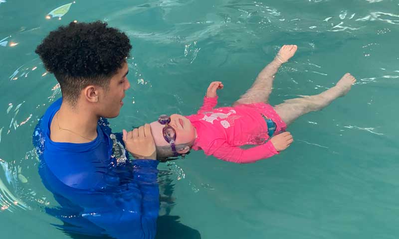 An Njswim teacher works with a very young swim student in the pool 