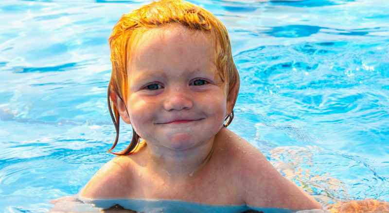 A cheerful young boy is beaming with happiness during his swimming lesson at Njswim