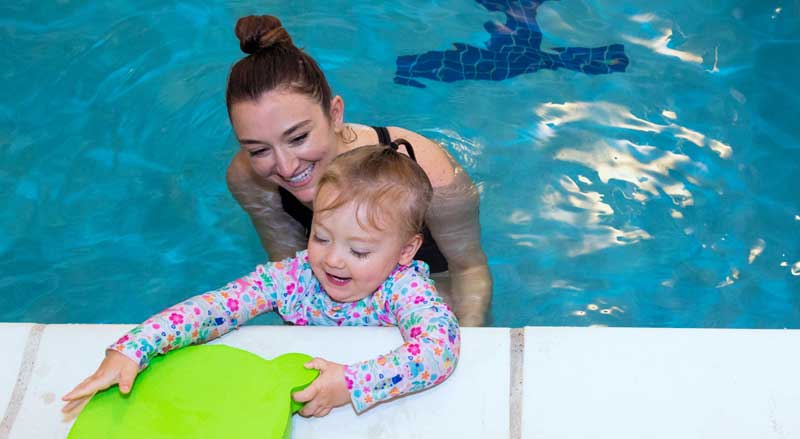 A swim teacher with a young child in pool