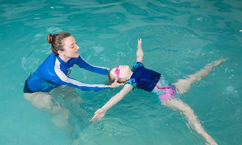 A young girl working on a swim skill with her swim teacher