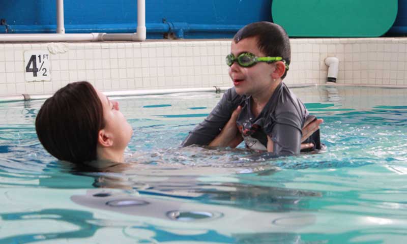 A young boy taking a swim lesson with his Njswim teacher
