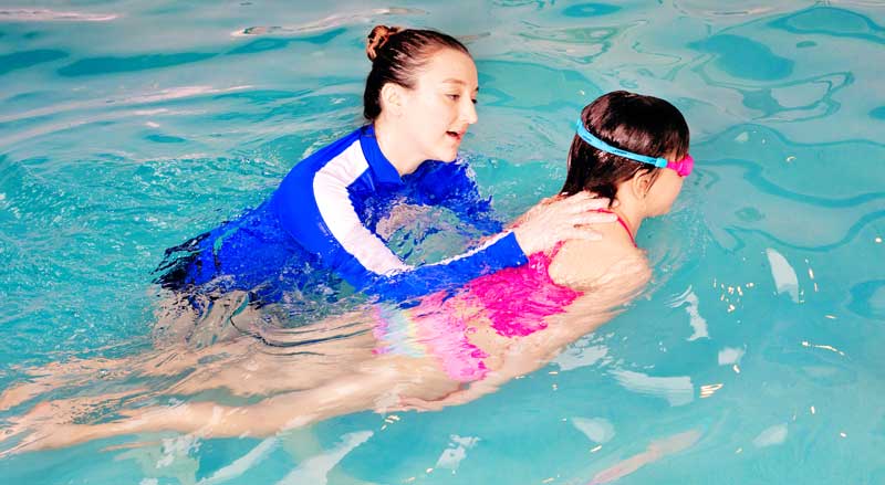 A Njswim teacher helps a young student in the pool