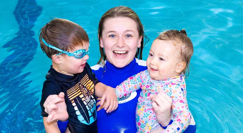 A Njswim teacher and young students are all smiles in the pool