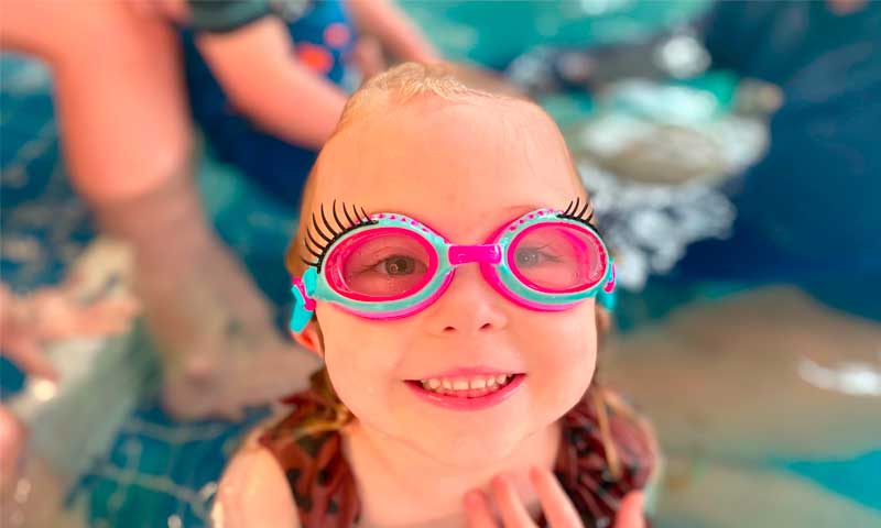 A young swimmer showing off her funny goggles in the pool