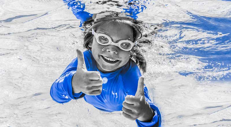 Njswim student smiling under water and giving a thumbs up