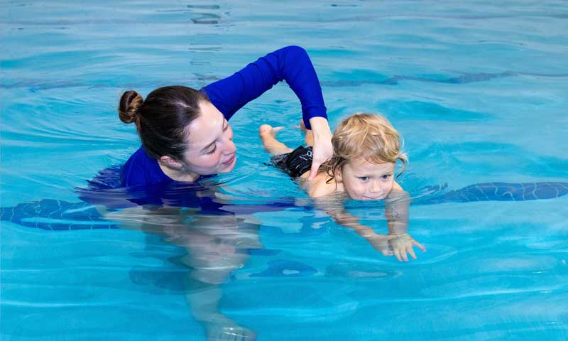 A Njswim teacher teaching swim lesson to a young toddler