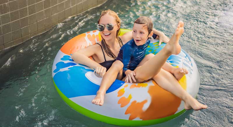 A woman and child going down a lazy river in a tube at a waterpark.