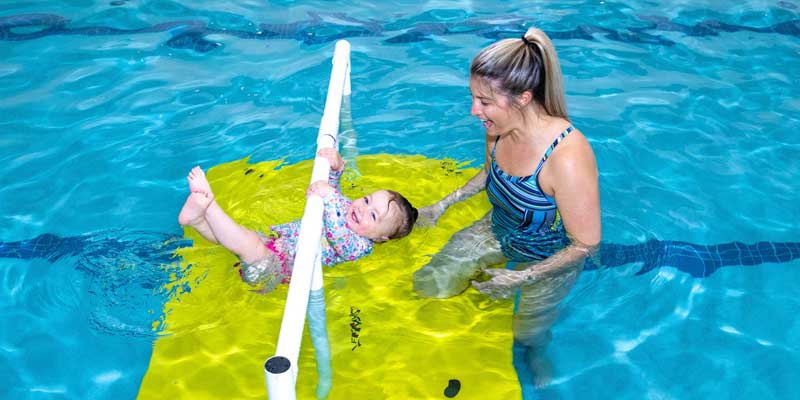 A toddler in the pool at Njswim Sparta with swim teacher having fun learning to float
