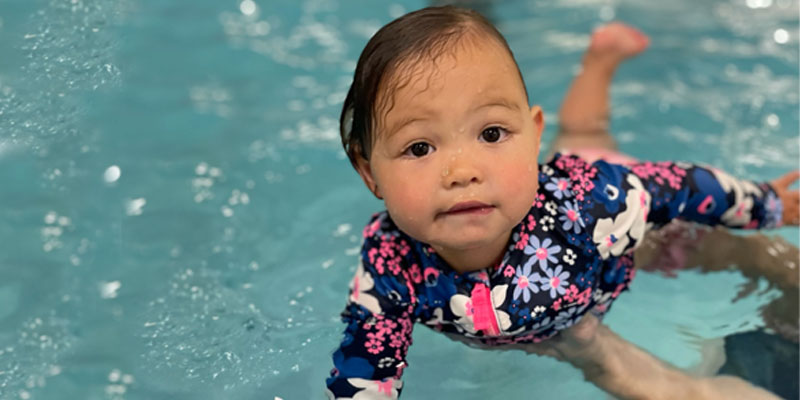 Baby girl in a pool with a parent