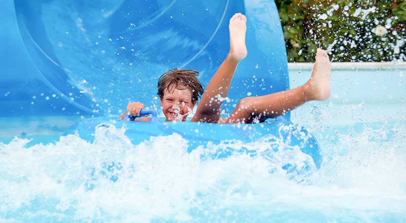 A kid having fun going down a water slide in a water park