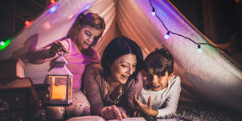 Mom reading to kids inside homemade fort, build-a-fort