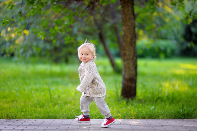 Cute happy toddler on the go on sidewalk