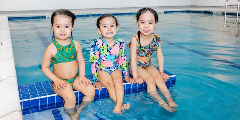 water-safety, three toddlers sitting with feet in swimming pool